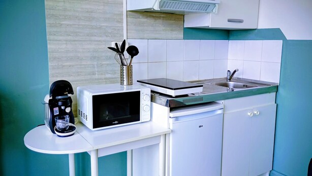 Una cocina compacta con microondas, cafetera y lavavajillas pequeño.