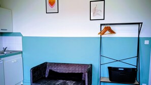 Una habitación con un sofá, un estante pequeño con una cesta y un cuadro en la pared.