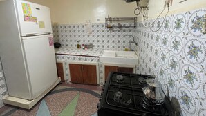 Een kleine keuken met een koelkast, fornuis, spoelbak en een decoratieve spatwand.
