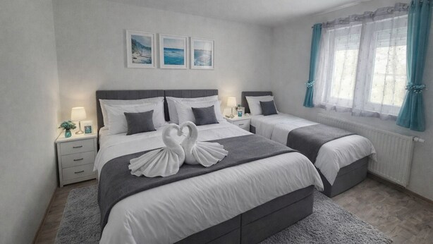 Een hotelkamer met twee bedden, een plafondventilator, een raam met gordijnen en kunst aan de muur.