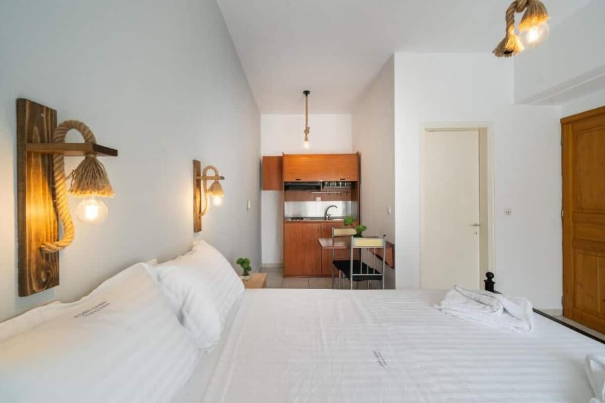 Una habitación pequeña con cama, kitchenette y puerta de madera.