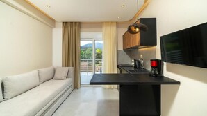 Un soggiorno moderno con divano, tavolino, TV a parete e angolo cucina con macchina del caffè.
