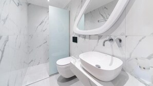 Un bagno moderno con lavandino bianco, un water e cabina doccia in vetro.