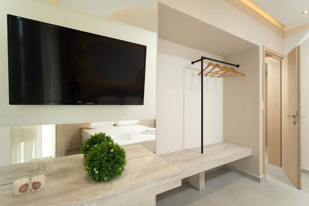 Un bagno moderno con una grande TV a schermo piatto, una panca, una piccola pianta e una porta in legno.
