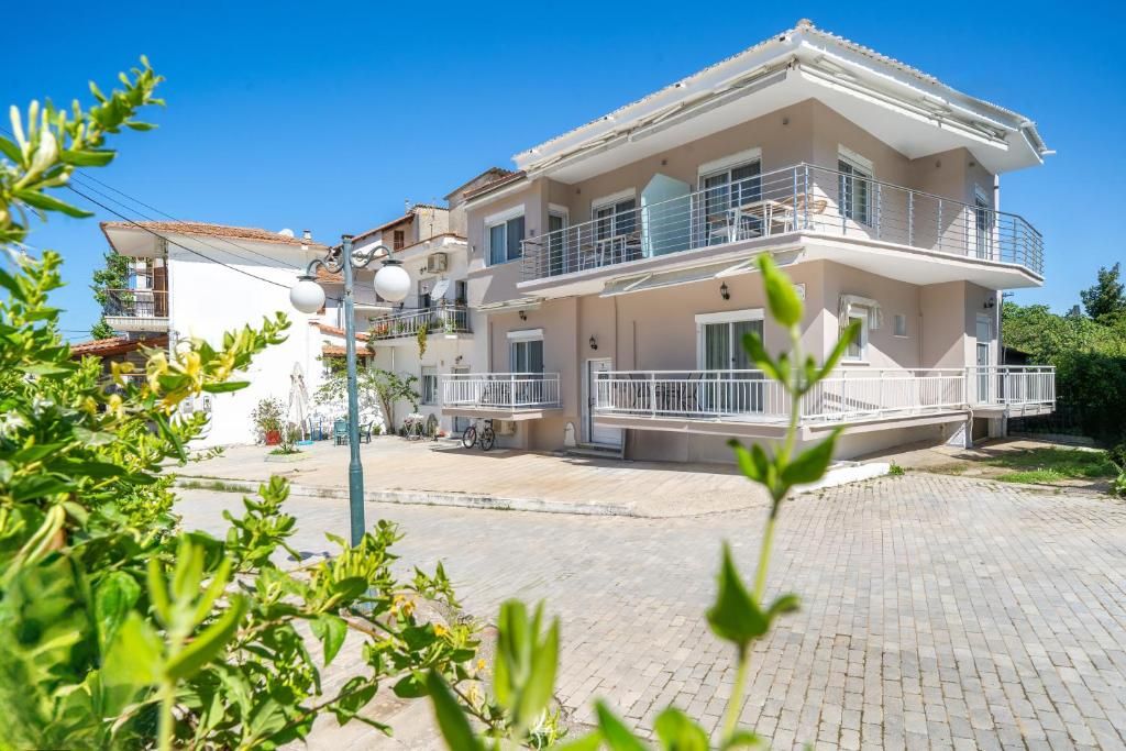 Un edificio residencial de varios pisos con balcones, un camino pavimentado y zonas verdes alrededor.
