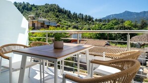 Una terrazza con tavolo e sedie, una pianta in vaso e vista su una collina con edifici.
