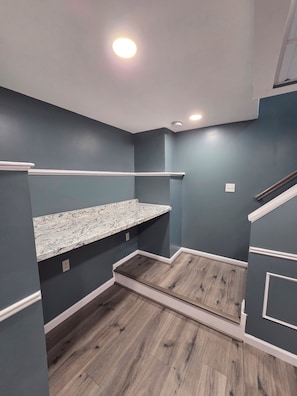 Una habitación con paredes azul oscuro, suelo de madera y encimera de mármol.