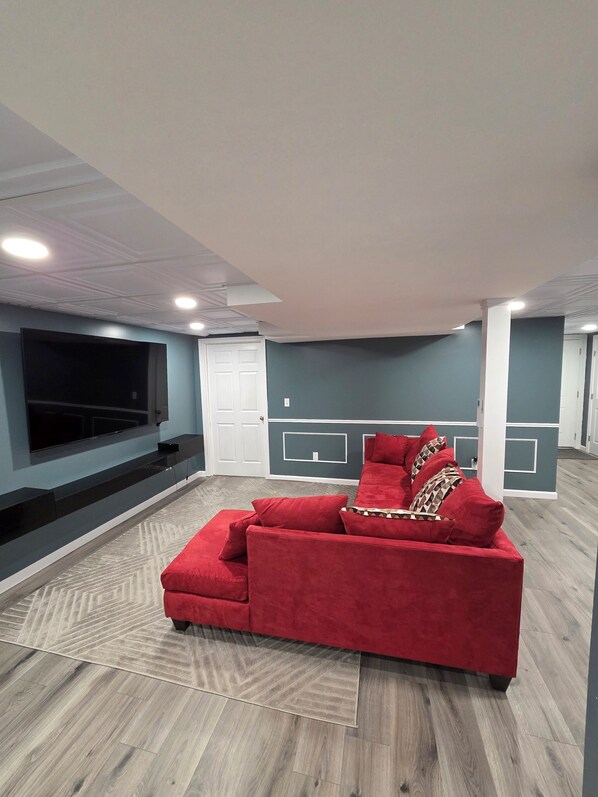 Una sala de estar moderna con un sofá rojo, un televisor de pantalla plana y una alfombra estampada.