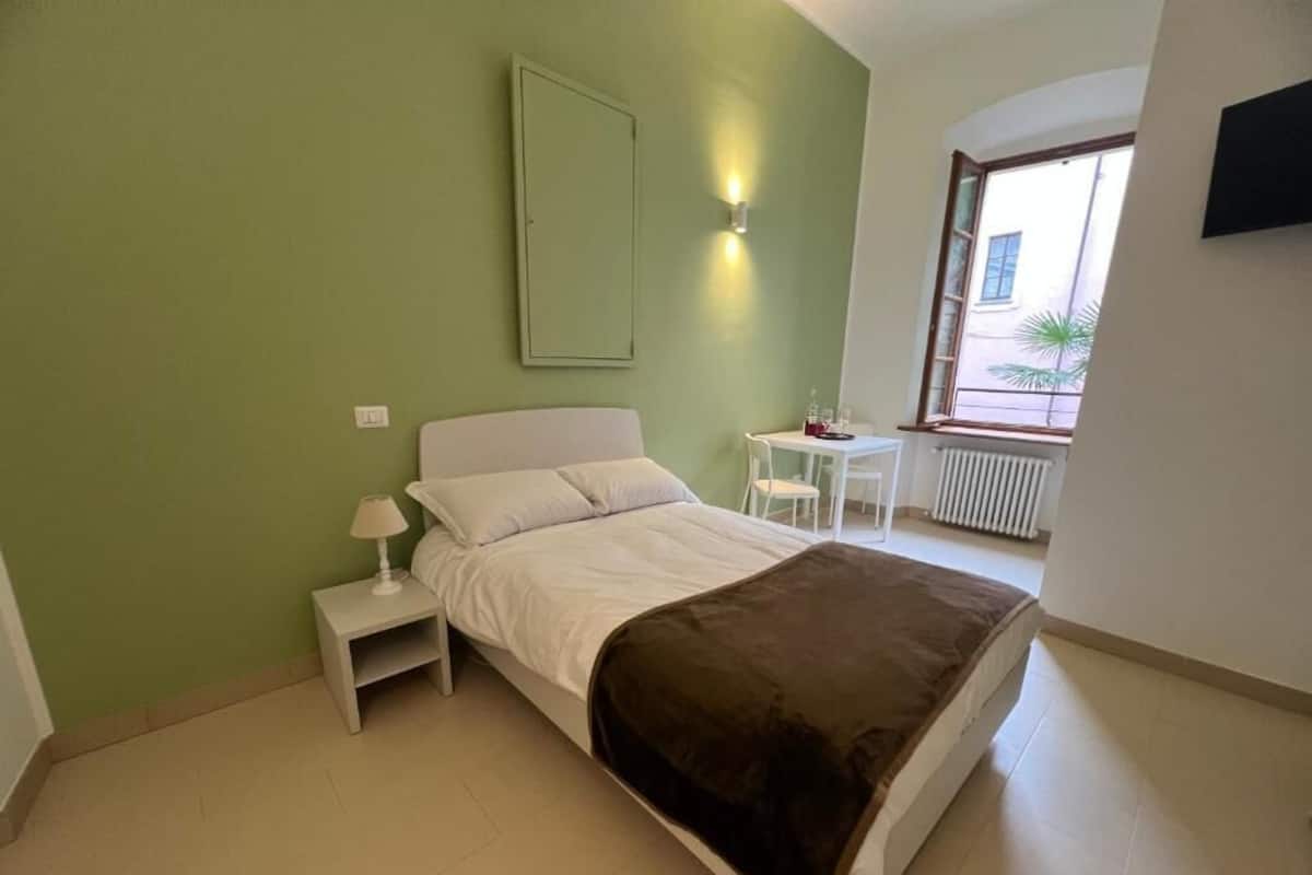 Ein Schlafzimmer mit Bett, Nachttisch, Tisch, Stuhl und Fenster.