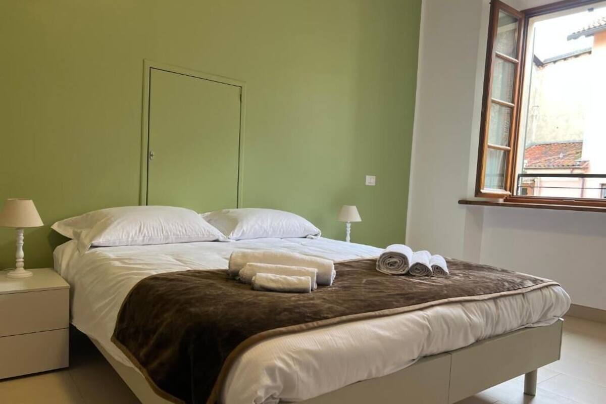 Ein Schlafzimmer mit einem Bett, zwei Nachttischen, einem Fenster und einer Tür.