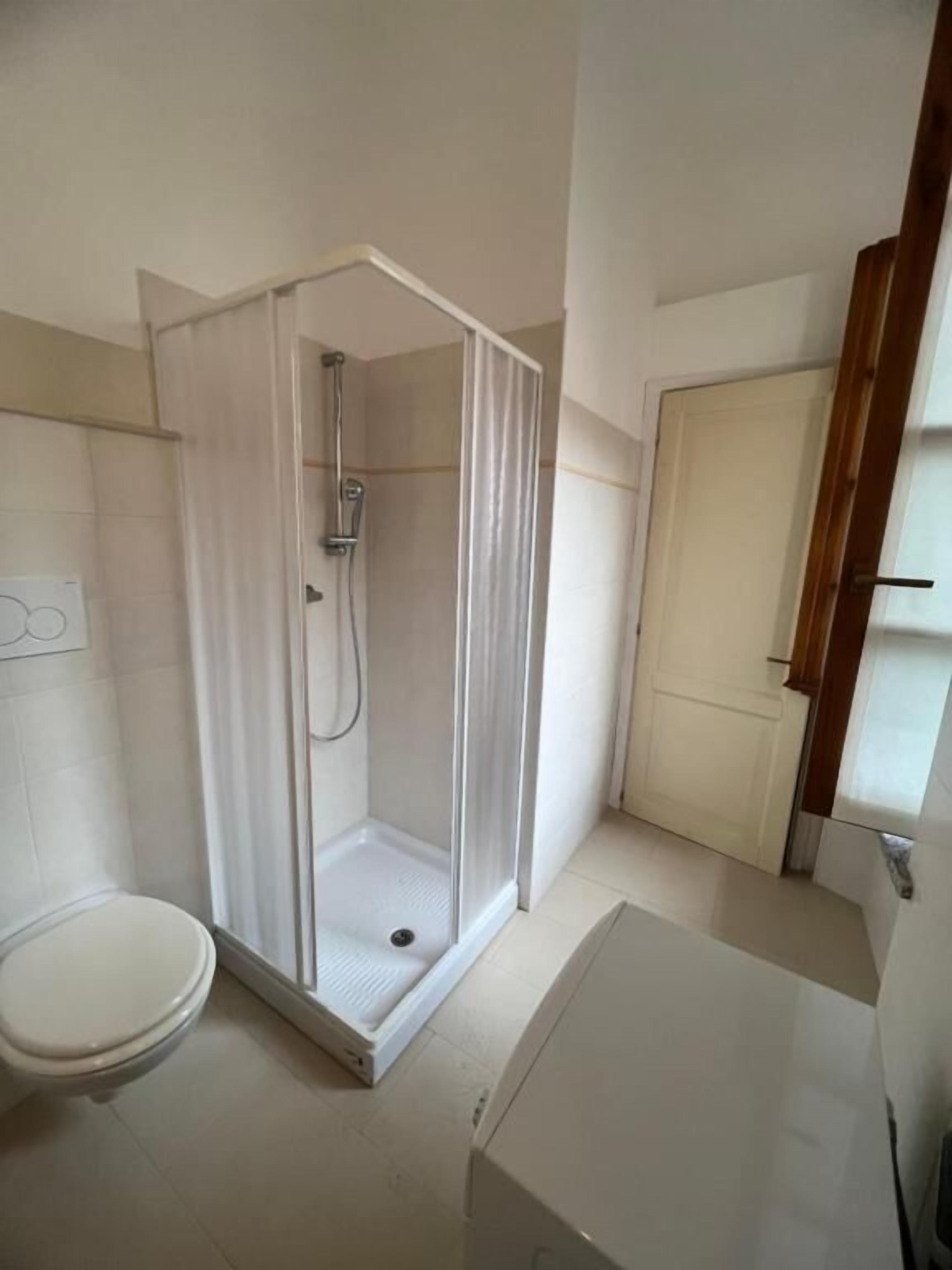 A bathroom with a shower enclosure, toilet, and sink.