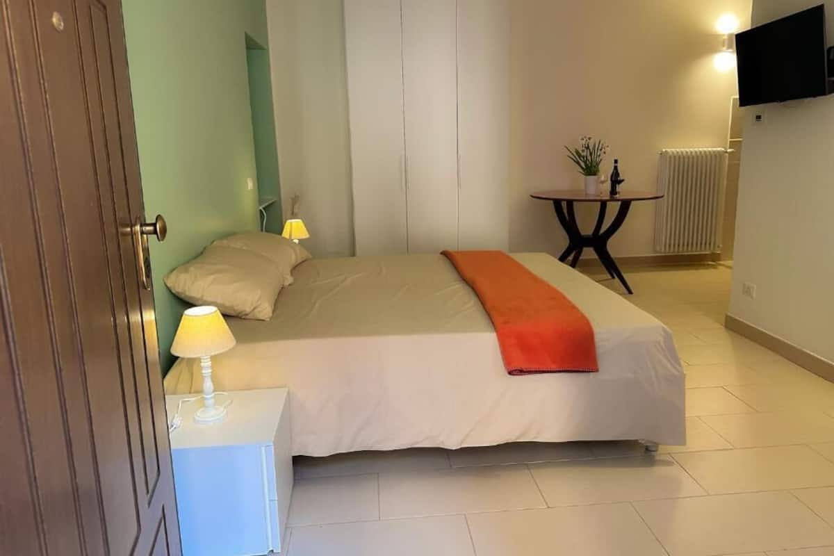 Ein Schlafzimmer mit Bett, Nachttischen, Lampe, Fernseher, Heizkörper und Kleiderschrank.