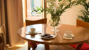 A round wooden table with a glass vase of white flowers, two cups, and a plate of cookies. - Luma Novara (Novara)