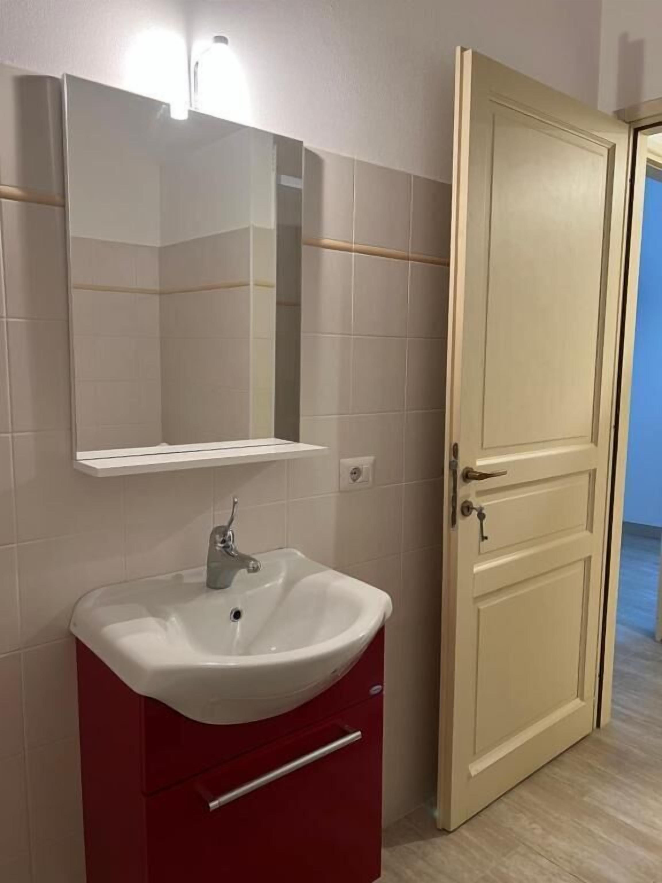 A bathroom with a white sink, a mirror, and a door.