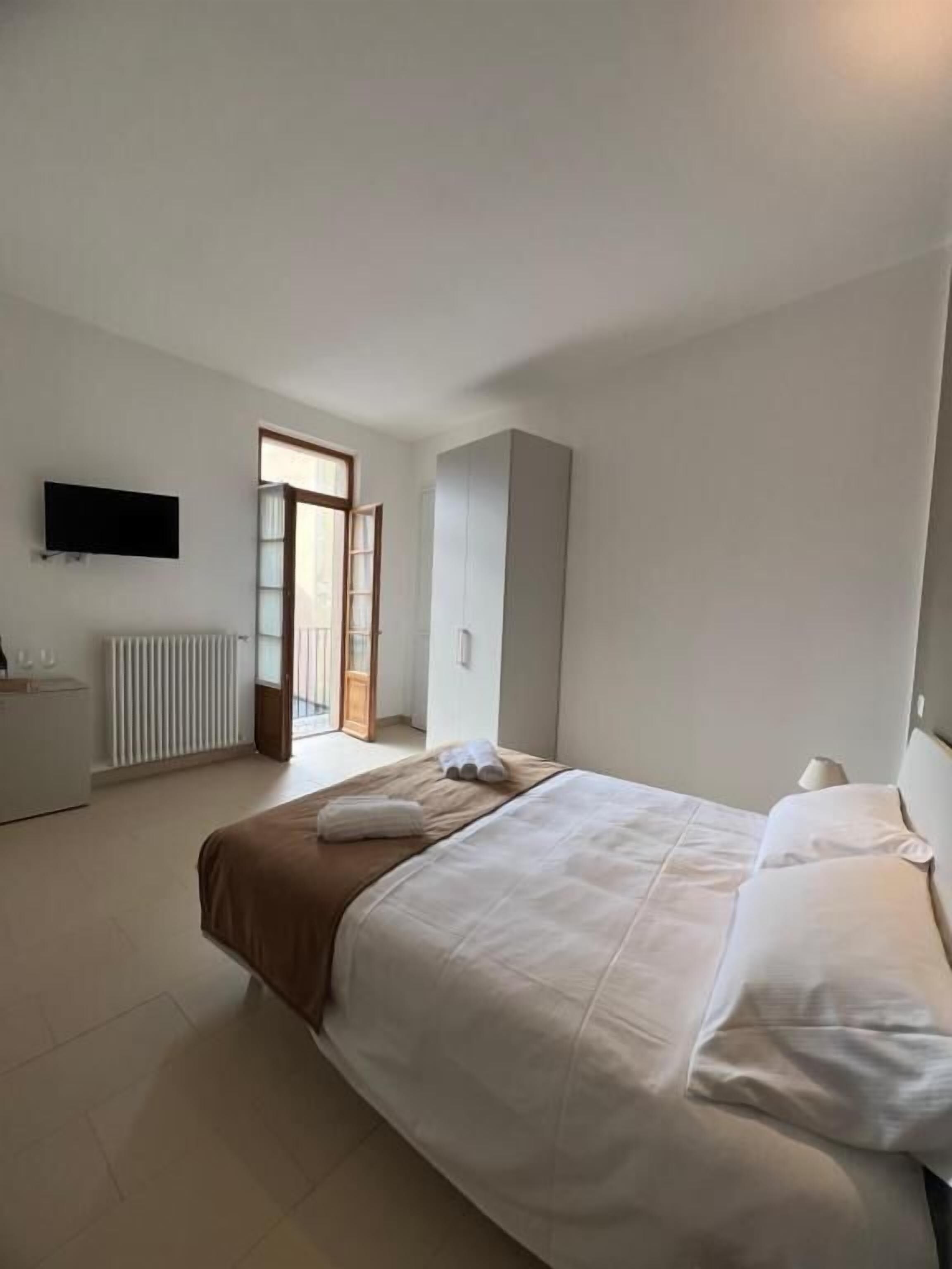 A bedroom with a bed, a dresser, a television, and a window.