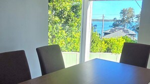 Ett rum med ett stort fönster, ett träbord och två stolar.