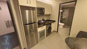 Eine kompakte Küche mit Kühlschrank, Mikrowelle, Spüle und Waschmaschine.