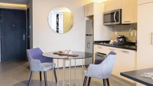 Eine moderne Küche mit Mikrowelle, Backofen und Spüle. Ein runder Tisch mit zwei Stühlen und ein dekorativer Spiegel an der Wand.