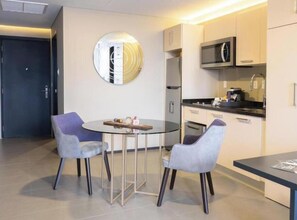 A modern kitchen with a microwave, oven, and sink. There is a round table with two chairs and a decorative mirror on the wall. - Twin Room (Ciudad de México)