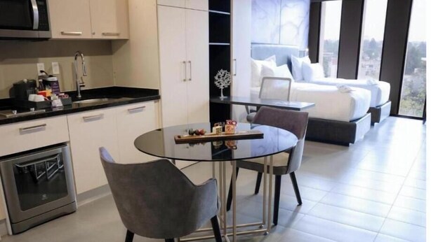 Eine moderne Küche mit Essbereich, ein Bett mit Blick auf die Stadt und ein kleiner Tisch mit Dekoration.