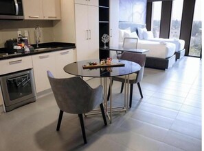 Een moderne keuken met een eethoek, een bed met uitzicht op de stad, en een bijzettafeltje met decoratieve objecten.