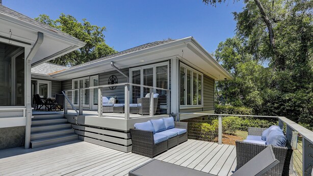 A covered deck with outdoor furniture, a staircase leading to an upper level, and a view of the surrounding greenery. - 7 Rum Row - Private Pool, Golf Views & Walk to the Beach in Palmetto Dunes (Hilton Head Island)