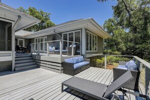 Una terrazza coperta con mobili da esterno, una scala che conduce a un livello superiore e vista sul verde circostante.