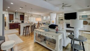 A spacious living area with a kitchen, dining space, and a fireplace. - 7 Rum Row - Private Pool, Golf Views & Walk to the Beach in Palmetto Dunes (Hilton Head Island)