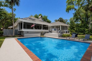 Ein modernes Haus mit Swimmingpool, einer überdachten Terrasse und einer Flagge.