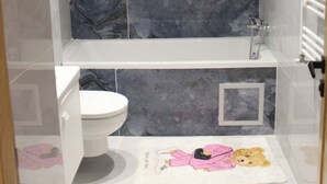 A modern bathroom with a marble backsplash, a mounted TV, a bathtub, a toilet, and a towel rack. - Carthage Eden (Tunis)