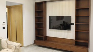A living room with a large flat-screen TV mounted on a wooden wall unit with shelves. - Carthage Eden (Tunis)