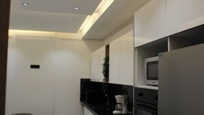 A modern kitchen with white cabinets, a black countertop, a microwave, and a coffee maker. - Carthage Eden (Tunis)