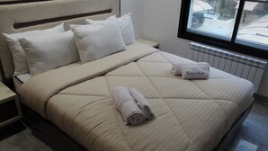 A neatly made bed with a quilted cover, a pillow, and a rolled towel on the bed. - Carthage Eden (Tunis)