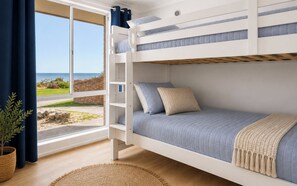 A bunk bed with a view of the sea, a plant, and a woven rug. - Wake up to ocean views and wander barefoot across to the beach for a morning swim, coffee or sunset walk along the shoreline  Perfect for families, couples or work trips, the home offers (Safety Bay)
