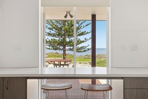 A kitchen with a view of a wooden deck and a large tree. - Wake up to ocean views and wander barefoot across to the beach for a morning swim, coffee or sunset walk along the shoreline  Perfect for families, couples or work trips, the home offers (Safety Bay)