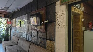 Et værelse med en marmorvæg, en sofa, en dekorativ panel og en dør med indviklede detaljer.