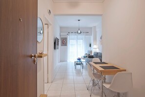 A modern interior with a wooden door, a dining area with a table and chairs, a sofa, and a ceiling light fixture. - Urban Muse Exarchia (Athina)
