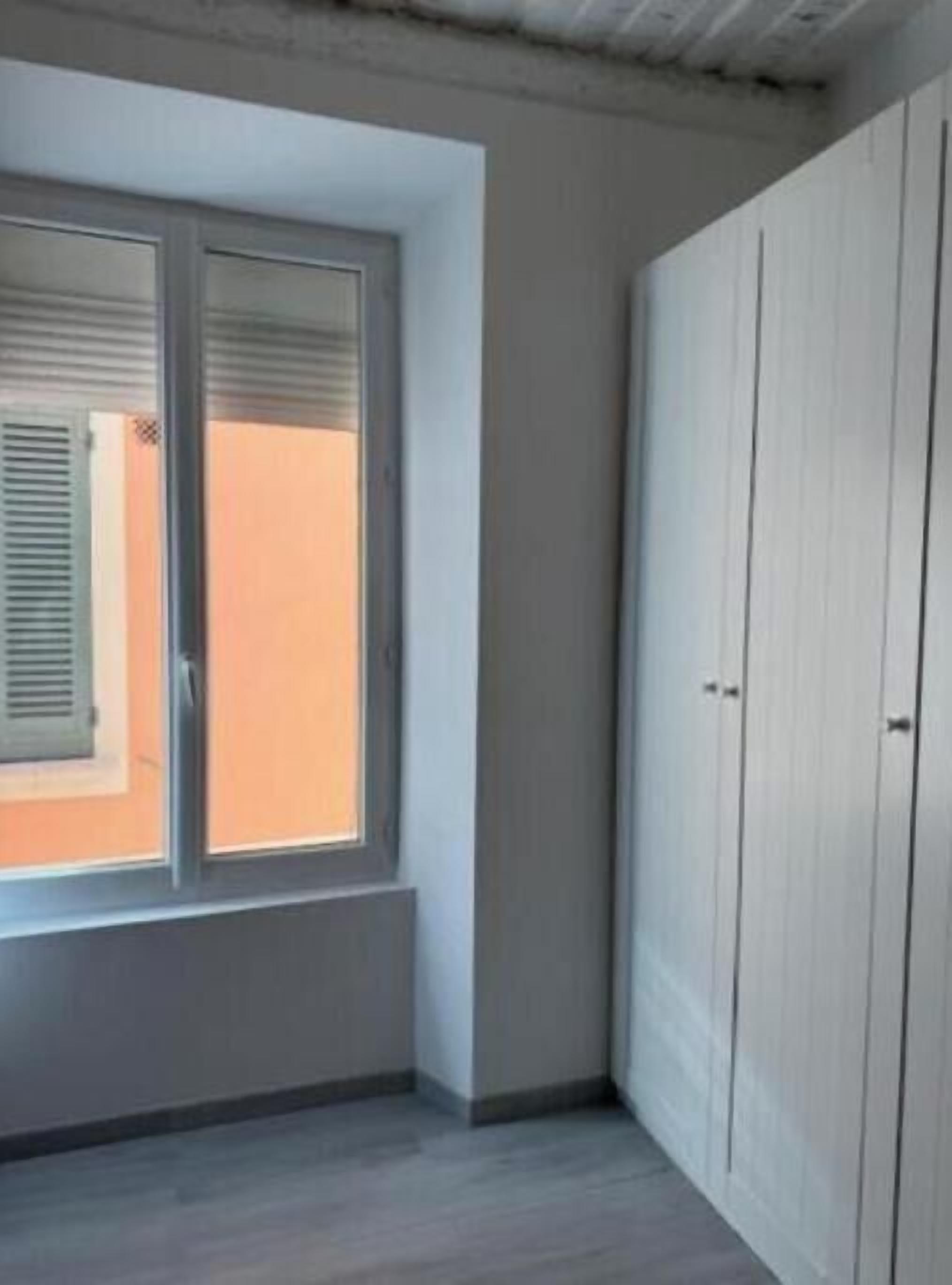 Ein Zimmer mit Fenster, Schrank und Tür.