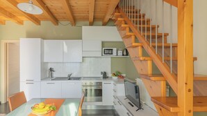 Una cocina moderna con armarios blancos, horno de acero inoxidable, microondas y una escalera de madera.