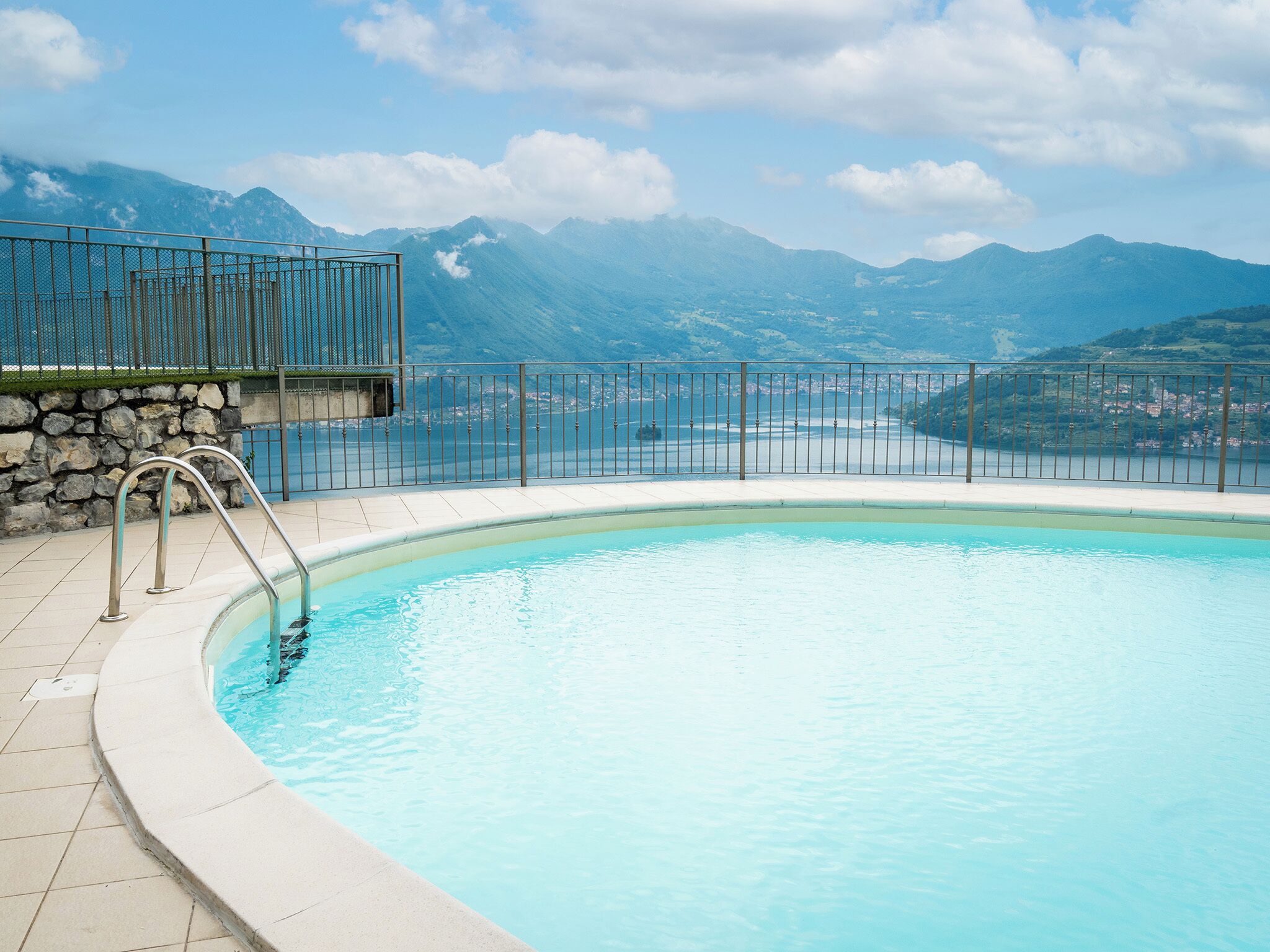 A swimming pool with a view of mountains and a stone wall.