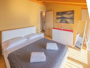 A bedroom with a bed, a dresser, a mirror, and a painting on the wall.