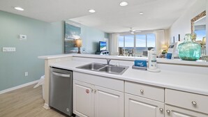A kitchen with a dishwasher, double sink, and a large window with a view. - Emerald Key 302 by Liquid Life (Orange Beach)