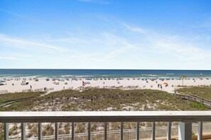A beach with a wooden boardwalk, a flag, and beach umbrellas.