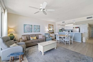 A modern living room with a sofa, chairs, a coffee table, a dining area, and a kitchen.