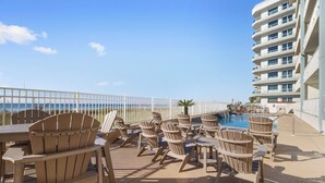 A poolside area with Adirondack chairs and a view of the ocean. - Emerald Key 302 by Liquid Life (Orange Beach)