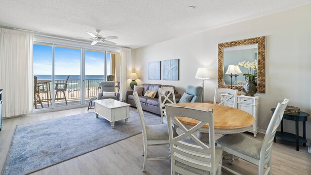 A spacious living room with a balcony, a dining area, and a large mirror. - Emerald Key 302 by Liquid Life (Orange Beach)