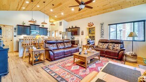 A spacious living area with a ceiling fan, wooden flooring, and a large window. - Escape to Alpine! Outstanding Cabin w/ Deck & Yard (Alpine)