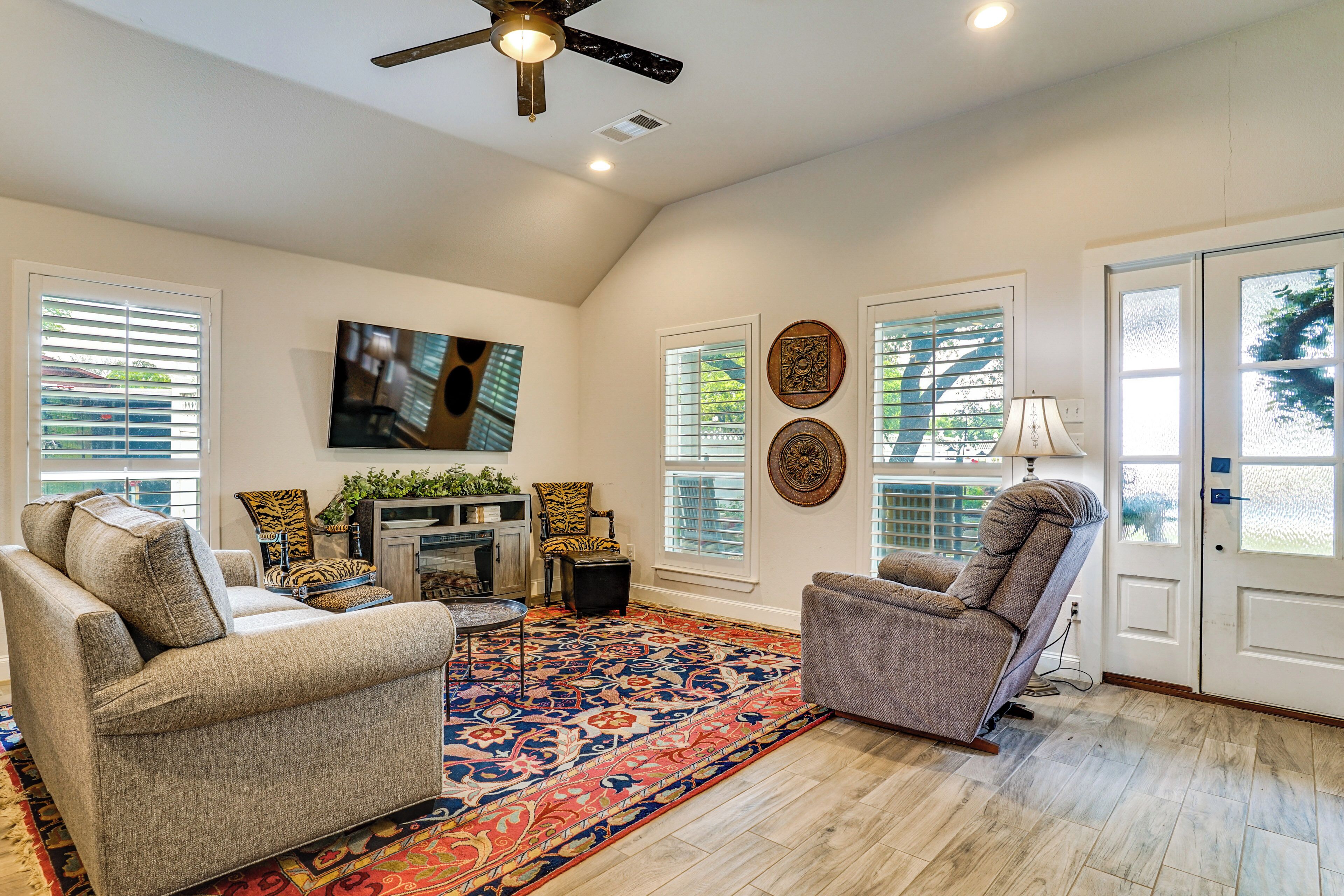 A living room with two sofas, a fireplace, a ceiling fan, and decorative wall art.