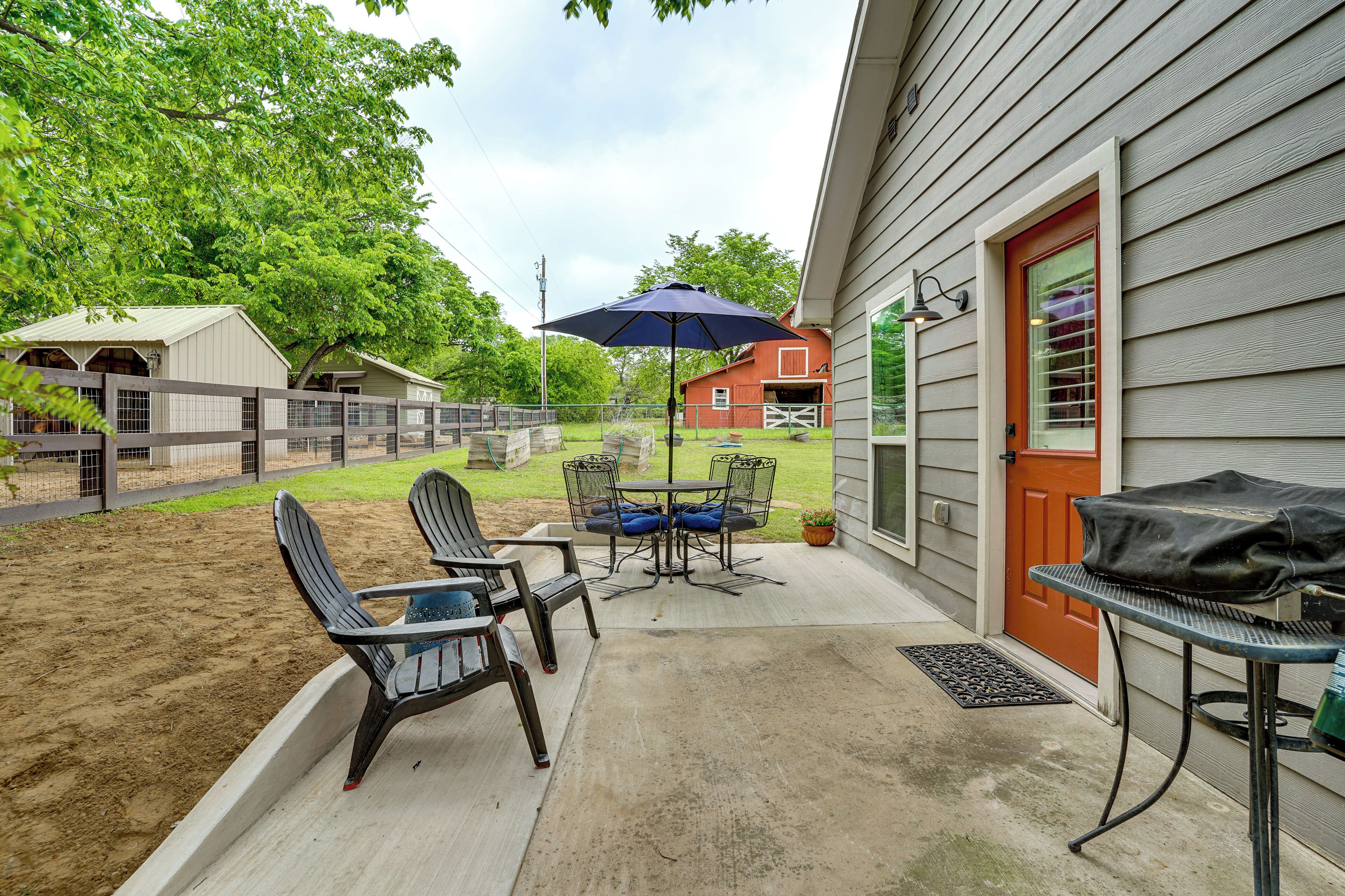 A patio with outdoor furniture, a barbecue grill, and a red door.
