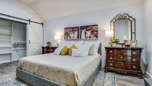 A bedroom with a bed, a dresser, a mirror, and two paintings on the wall. - Backyard Bungalow w/ Pool & Country Views (Argyle)